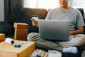 adolescente asiático detém um cartão de crédito e está usando um conceito on-line de compras de computador portátil.