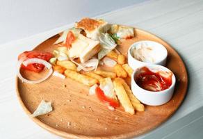 junk food é comida desperdiçada ou estragada e outros resíduos, em um prato de madeira de uma cozinha. foto