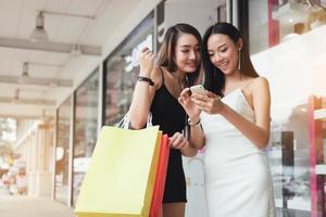 duas linda mulher usando smartphone no shopping. foto