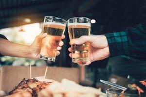 dois amigos brindando e brindando com um copo de cerveja. foto