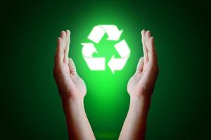 mão jovem asiática segurando o ícone de reciclar e fundo verde. foto