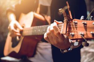 homem hipster asiático mão esquerda pegar acorde e tocar música. foto