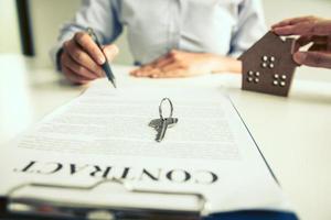 agentes residenciais estão enviando canetas para clientes assinando um contrato para comprar uma nova casa. foto