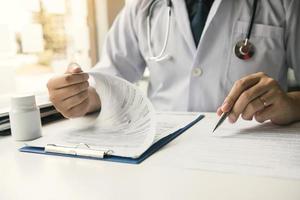 mão do médico segurando a caneta escrevendo a lista de histórico do paciente no bloco de notas e conversando com o paciente sobre medicação e tratamento. foto