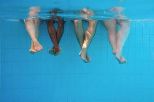 pernas de homem afro-americano com amigos caucasianos na piscina debaixo d'água. verão. conceito de férias, internacional e esporte. foto