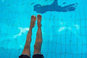 as pernas do homem afro-americano adulto debaixo d'água na piscina foto