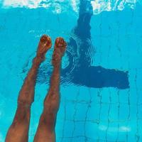 as pernas do homem afro-americano adulto debaixo d'água na piscina foto