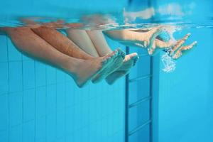 pernas da família debaixo d'água na piscina. foto