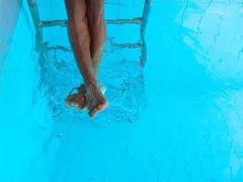 as pernas do homem afro-americano adulto debaixo d'água na piscina foto