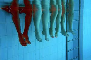 pernas de homem afro-americano com amigos caucasianos na piscina debaixo d'água. verão. conceito de férias, internacional e esporte. foto