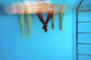 pernas de homem afro-americano com amigos caucasianos na piscina debaixo d'água. verão. conceito de férias, internacional e esporte. foto