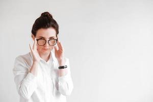 mulher de óculos ópticos e uma camisa branca em um fundo branco. copiar, espaço vazio para texto foto