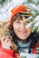 retrato de uma mulher em uma jaqueta vermelha quente e chapéu em uma floresta de inverno nevado. copiar, espaço vazio para texto foto