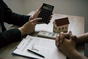 os agentes estão calculando a taxa de pagamento do empréstimo ou o valor dos prêmios de seguro para clientes que entram em contato com a compra de uma nova casa no escritório. foto