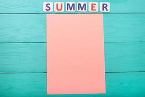 palavra verão e papel com espaço de cópia em fundo azul de madeira foto