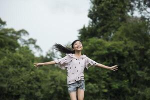 menina feliz e fofa correndo na grama do parque foto