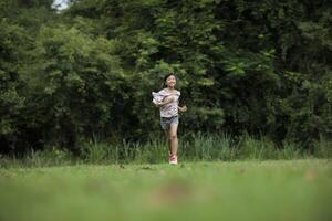 menina feliz e fofa correndo na grama do parque foto