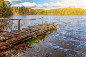 lago ou rio da floresta no dia de verão e velha doca ou cais de madeira rústica foto