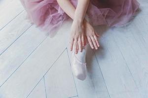 mãos de bailarina coloca sapatilhas na perna na aula de dança foto