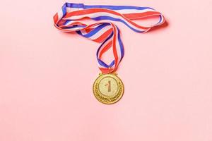 vencedor de design simplesmente plano ou medalha de troféu de campeão de ouro isolada em fundo colorido rosa. vitória primeiro lugar da competição. conceito de vitória ou sucesso. espaço de cópia da vista superior. foto