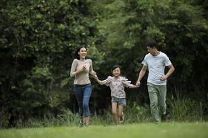 família feliz está se divertindo mãe, pai e filha estão correndo no parque. foto