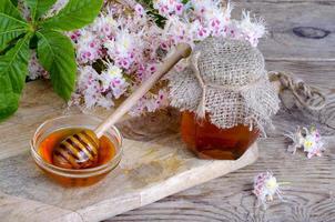 mel de castanha perfumado em jarra com flores em flor. foto