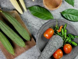 pimentões e tomates em um almofariz, receita de milho vegetal e luffa acutangula com molho de tomate. conceito de preparação de alimentos foto