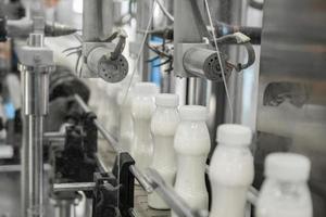 garrafas de leite de plástico na correia transportadora. equipamentos na fábrica de laticínios foto
