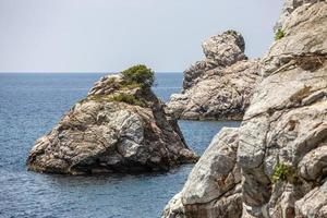 grande rocha nas águas azuis da praia de stafilos, skopelos, ilha de skopelos, grécia. foto