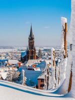 uma antiga cidade alsaciana sob a neve. a torre do sino da catedral e os telhados das casas medievais. foto