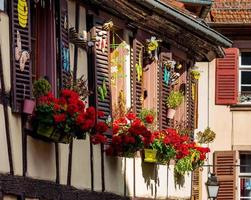 janelas alsacianas clássicas em uma casa em enxaimel, decorada com esculturas de madeira e flores foto