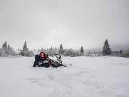 duas meninas, irmãs, brincam com um cachorro corgi em um campo nevado nas montanhas foto