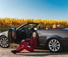 uma linda garota perto de um carro quebrado em um campo, um conversível retrô foto