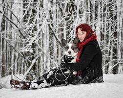 retrato de uma menina na neve com seu animal de estimação - corgi. foto