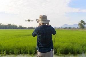 jovem agricultor inteligente controlando a pulverização de fertilizantes e pesticidas por drones sobre terras agrícolas, inovações de alta tecnologia e agricultura inteligente foto