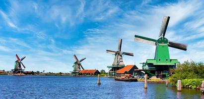 moinho holandês na zona rural verde perto de amsterdam, holanda, com céu azul e água do rio. foto