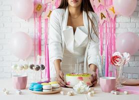 mulher com roupas brancas de festa preparando a mesa de aniversário foto