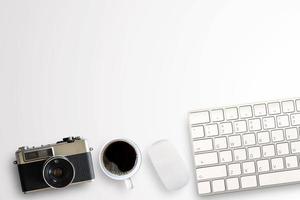 xícara de café e câmera vintage com mini mouse e teclado sem fio em fundo branco no local de trabalho do escritório.