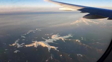 imagens aéreas da janela de um avião sobre montanhas cobertas de neve. foto