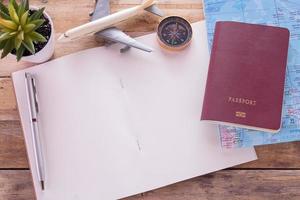caderno em branco, passaporte, bússola, avião e mapa na mesa de madeira.