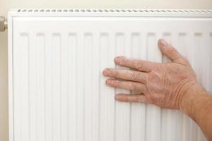 homem de macacão de trabalho usando chave durante a instalação do radiador de aquecimento no quarto. encanador instalando sistema de aquecimento no apartamento. conceito de instalação de radiadores, trabalhos de canalização e renovação de casas foto