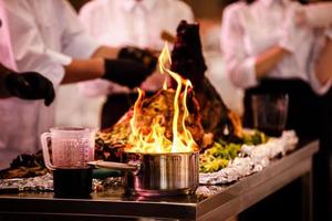 programa de culinária, o cozinheiro prepara comida em uma frigideira com fogo. o chef prepara comida com show de fogo no restaurante. foco seletivo foto