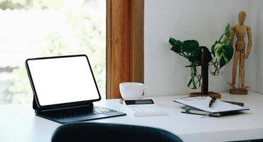 tablet digital com tela branca em branco na mesa. espaço de trabalho no conceito de escritório moderno. foto