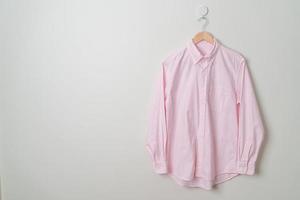 camisa pendurada com cabide de madeira na parede foto