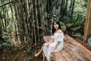 jovem mulher asiática relaxa na floresta, linda fêmea feliz usando o tempo de relaxamento na natureza. mulheres de estilo de vida viajam no conceito de floresta. foto
