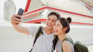 casal de blogueiros asiáticos viaja em bangkok, tailândia, doce casal usando a visualização de foto de selfie de telefone celular enquanto passa um tempo doce em viagem de férias ao pôr do sol. casal viaja no conceito de cidade.