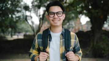 viajante homem asiático se sentindo feliz sorrindo para a viagem de férias da câmera em ayutthaya, Tailândia, mochileiro masculino desfrutar de sua jornada no incrível ponto turístico na cidade tradicional. conceito de viagens de homens de estilo de vida foto