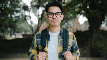 viajante homem asiático se sentindo feliz sorrindo para a viagem de férias da câmera em ayutthaya, Tailândia, mochileiro masculino desfrutar de sua jornada no incrível ponto turístico na cidade tradicional. conceito de viagens de homens de estilo de vida foto