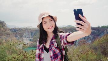 selfie de mulher mochileiro asiático no topo da montanha, jovem fêmea feliz usando o celular tomando selfie desfrutar de férias na aventura de caminhadas. mulheres de estilo de vida viajam e relaxam o conceito. foto