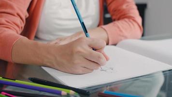 jovem mulher grávida asiática desenhando bebê na barriga e família no notebook. mãe se sentindo feliz sorrindo positivo e pacífico enquanto cuida da criança na mesa na sala de estar em casa conceito. foto